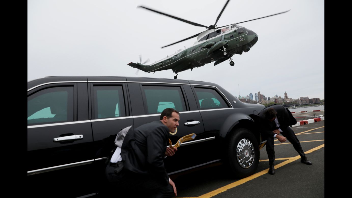 Secret Service agents use a presidential limousine to take cover from spraying water as Marine One lands in New York on Thursday, May 4.