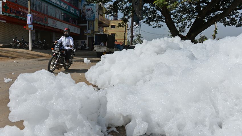 An Indian motorcyclist negotiates away from fluffy piles of foam at Varthur Kodi junction in east Bangalore on May 1, 2015. The innocuous-looking foam, which from a distance, looks like snow covering the road is nothing but toxic effluent caused by the polluted sewage water overflowing from nearby Varthur Lake. The foam is a result of the water in the lake having high content of ammonia and phosphate and very low dissolved oxygen. Sewage from many parts of the Bangalore is released into the lake, leaving it extremely polluted. The foam spilled onto Varthur Main Road, causing a traffic pile up recently besides spreading unbearable stench in the air for about three kilometre stretch near the Whitefield, which houses several IT companies at it Softare Technology Parks of India (STPI). AFP PHOTO/Manjunath KIRAN        (Photo credit should read MANJUNATH KIRAN/AFP/Getty Images)
