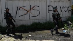 Philippine soldiers walk past Islamic State (IS) group graffiti in Marawi on the southern island of Mindanao on May 31, 2017, as fighting between government forces and Muslim militants rages on the ninth day.
Philippine security forces have killed 89 Islamist militants during more than a week of fighting in a southern city but the gunmen are still offering strong resistance and holding hostages, the military said on May 31. / AFP PHOTO / TED ALJIBE        (Photo credit should read TED ALJIBE/AFP/Getty Images)