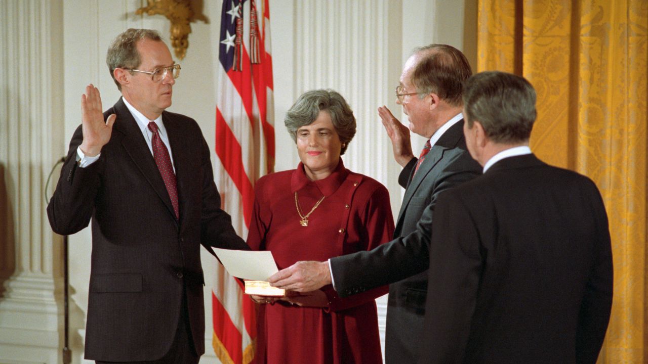 Kennedy is joined by his wife as he is sworn in by Chief Justice William Rehnquist on February 18, 1988. Reagan is on the right.