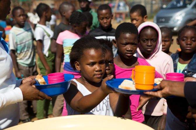 On May 7, 2017 in South Africa, (foreground) a girl receives a snack and a drink at the Isibindi Safe Park in Soweto Township, in the city of Johannesburg. 