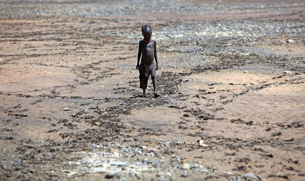 A boy from the remote Turkana tribe in Northern Kenya walks across a dried up river near Lodwar, Kenya. Millions of people across Africa are facing a critical shortage of water and food, a situation made worse by climate change. 