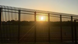 The sun sets through fencing along the Mexican border in Eagle Pass, Texas.