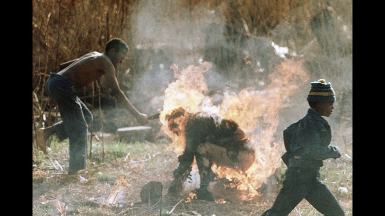 During clashes between rival political parties -- the African National Congress and the Inkatha Freedom Party -- a young man clubs the burning body of Lindsaye Tshabalala in Soweto, South Africa, on September 15, 1990. Violence in the early '90s between the two groups left thousands dead.