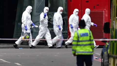 A group of police forensic officers walks in the street outside Borough Market.