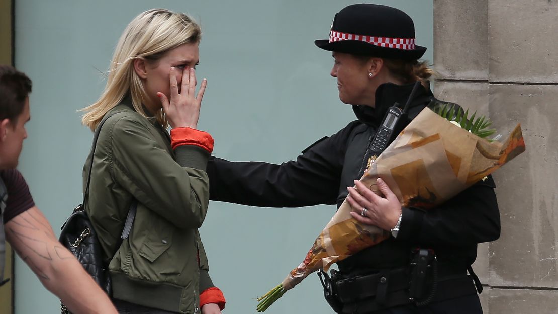 A woman reacts after asking a Police officer to lay flowers near London Bridge.