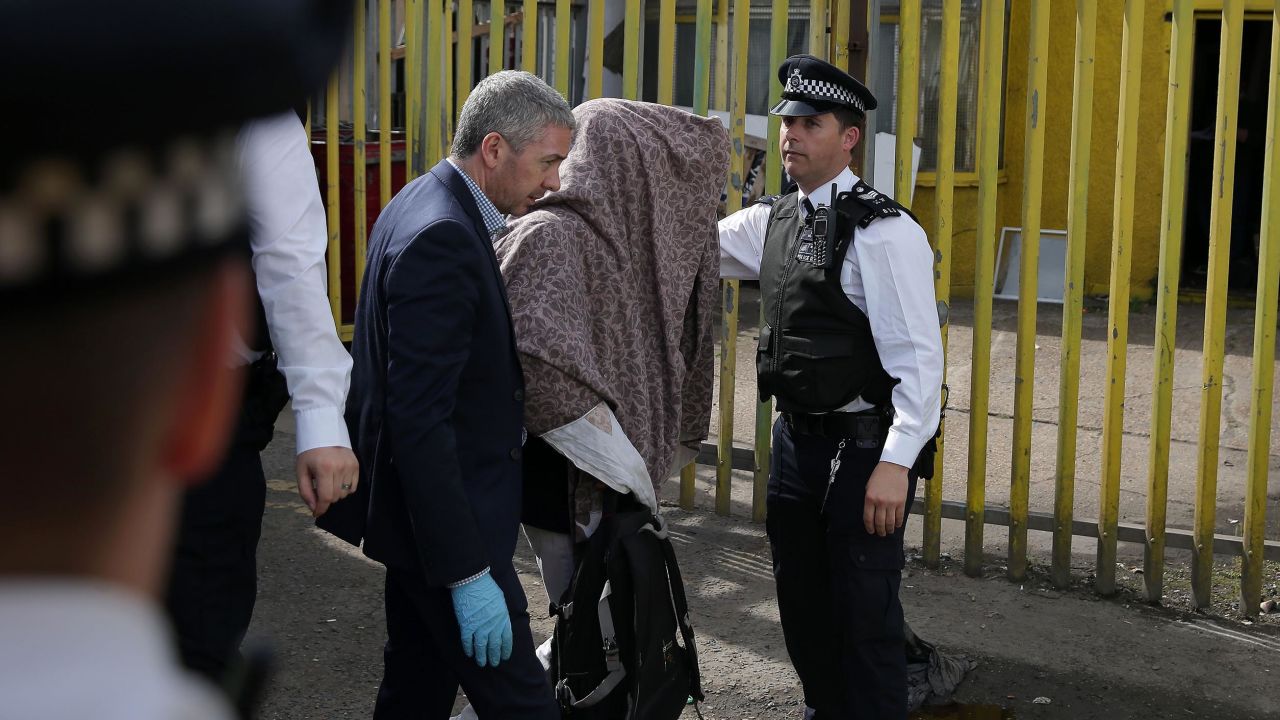 Police officers escort a person, with their head covered, to a police van, in Barking, east London on June 5, 2017, following a dawn raid on a property (R), as thier investigations continue following the June 3 terror attacks in central London.
Police carried out fresh raids and arrested "a number of people" on Monday after the Islamic State group claimed an attack by three men who mowed down and stabbed revellers in London on June 3, killing seven people, before being shot dead by officers. / AFP PHOTO / Daniel LEAL-OLIVAS        (Photo credit should read DANIEL LEAL-OLIVAS/AFP/Getty Images)