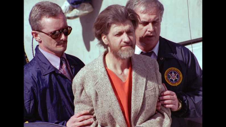 Shown on April 4, 1996, the day after his arrest, <a href="index.php?page=&url=http%3A%2F%2Fwww.cnn.com%2F2013%2F08%2F14%2Fjustice%2Fgallery%2Fcrimes-of-the-century-unabomber%2Findex.html">the Unabomber</a>, Ted Kaczynski, is led by FBI agents out of a Montana federal courthouse. Starting in 1978, Kaczynski had carried out a series of deadly bombings that killed three people and injured 24, while he managed to elude authorities. After The New York Times and The Washington Post published the Unabomber's 35,000 word manifesto, a tip from Kaczynski's brother led investigators to his remote Montana hideout.