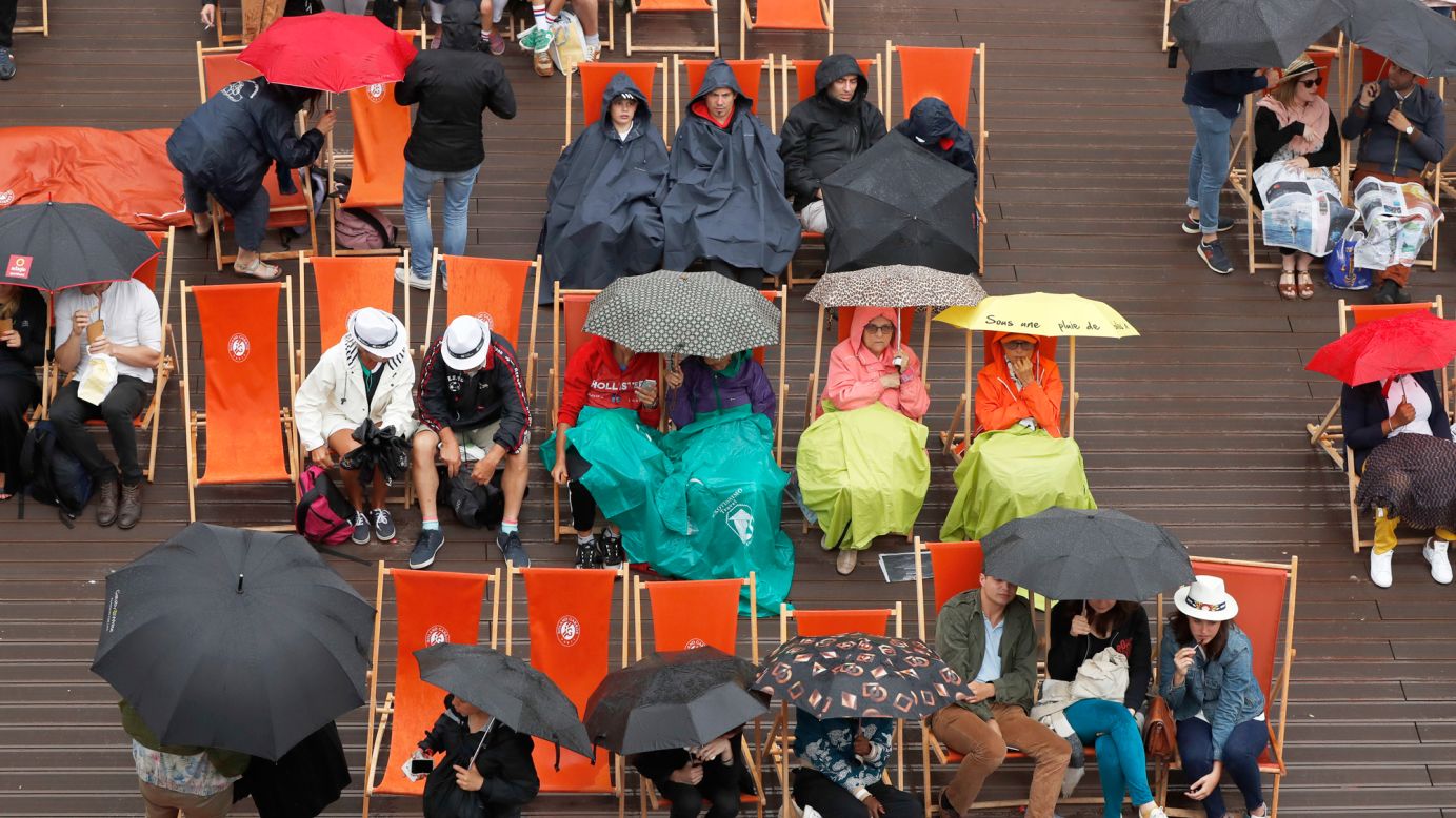 Spectators break out their umbrellas after French Open play was suspended because of rain on Saturday, June 3.