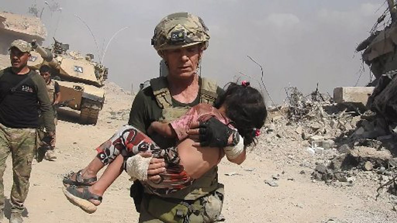 Dave Eubank from the "Free Burma Rangers" volunteer organization carries a little girl to safety after spotting her hiding under her dead mother's hijab for two days. The child was rescued in western Mosul as gunfire raked the area. Photo courtesy of Free Burma Rangers (www.freeburmarangers.org/)