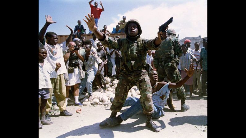 A US soldier stands in the midst of a chaotic situation in Haiti in 1994. US troops were deployed to Haiti that year to maintain order that had steadily deteriorated since a 1991 military coup that ousted the country's first democratically elected president, <a href="index.php?page=&url=http%3A%2F%2Fwww.cnn.com%2F2013%2F07%2F18%2Fworld%2Fjean-bertrand-aristide-fast-facts%2Findex.html">Jean Bertrand Aristide</a>. He was restored to power in October 1994.