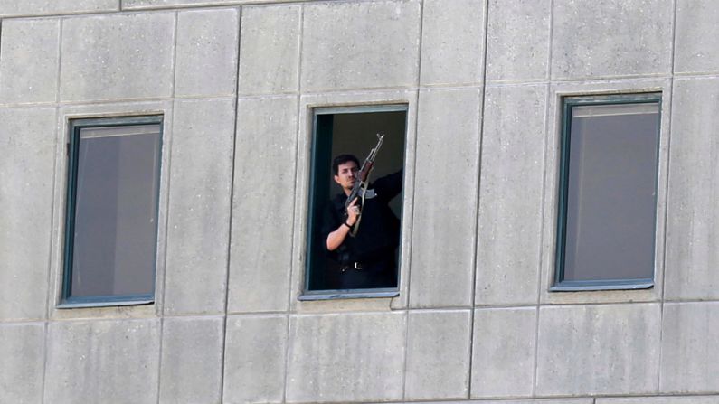 An armed security officer stands in a window of the parliament building during the attack. 