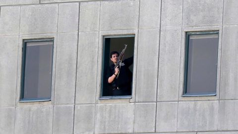 An armed security officer stands in a window of the parliament building during the attack. 
