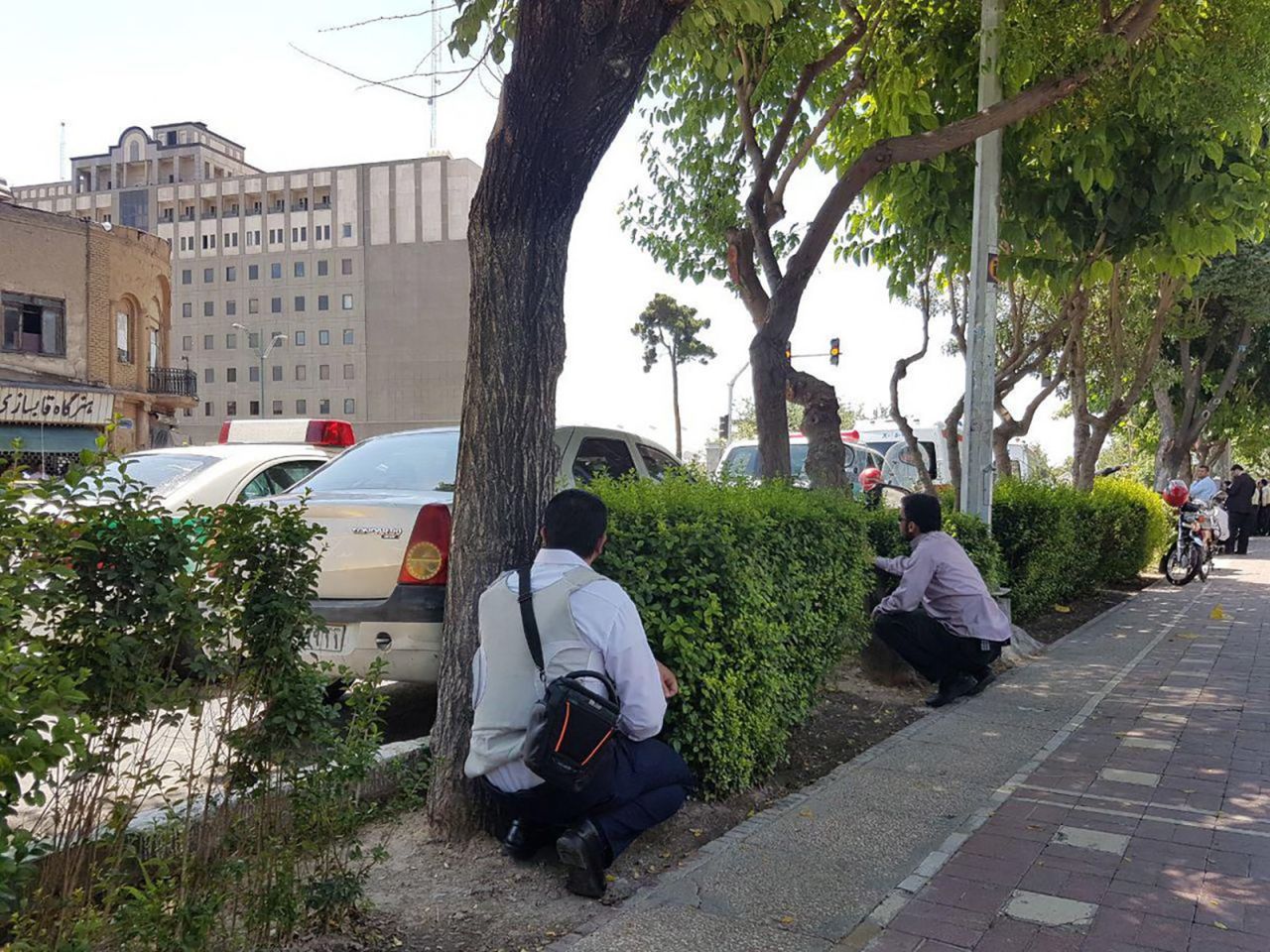 People duck behind shrubs during attacks Wednesday in and near Tehran.
