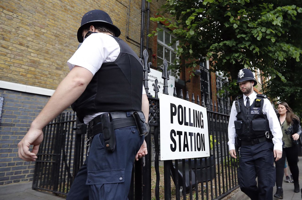 Police officers enter a polling station in London ahead of the arrival of Labour Party leader Jeremy Corbyn.
