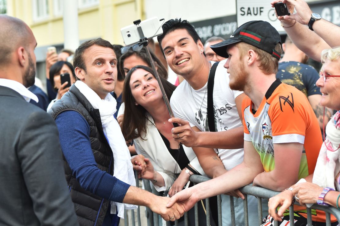 French President Emmanuel Macron poses for a selfie with supporters.