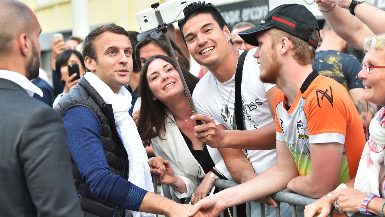 French President Emmanuel Macron poses for a selfie with supporters.