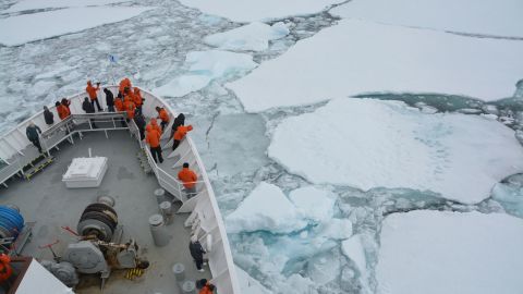 Explorers in bright parkas survey the Antarctic ice. 