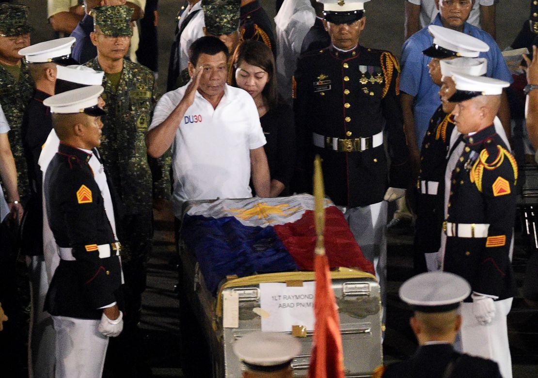 Philippine President Rodrigo Duterte (C) salutes in front of a flag-draped casket of a slain marine at a military base in Manila on June 11.