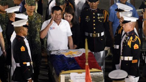 Philippine President Rodrigo Duterte (C) salutes in front of a flag-draped casket of a slain marine at a military base in Manila on June 11.