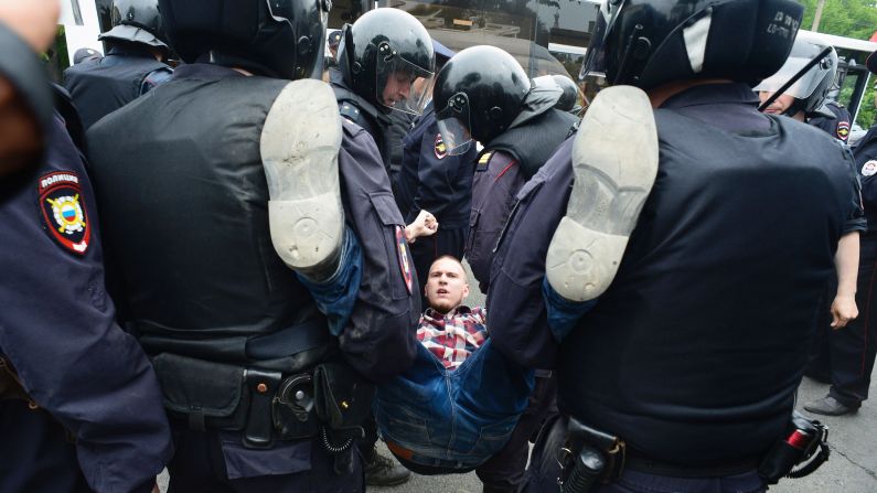 Russian police officers detain a participant of an unauthorized opposition rally in the center of Saint Petersburg on Monday, June 12.