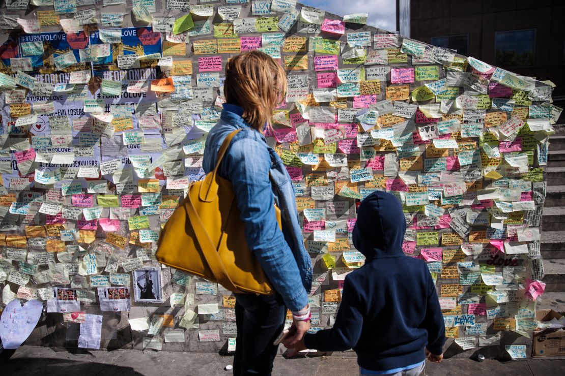A woman and child look at messages of condolence on a wall on the south end of London Bridge.