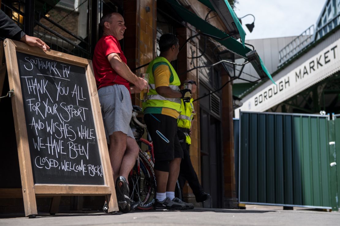 Cyclists drink beer outside the Southwark Tavern which reopened for business on Sunday.  