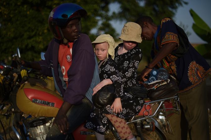 Two young sisters with albinism sit on a motorbike on Ukerewe. The island's reputation as a community in which those with albinism are greater integrated with those without it, has led some parents to relocate with their children.