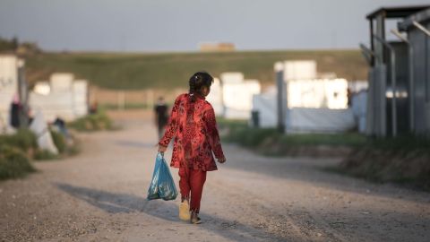 A girl runs with a plastic bag filled with food through Hasansham refugee camp in Iraq. FILE PHOTO.
