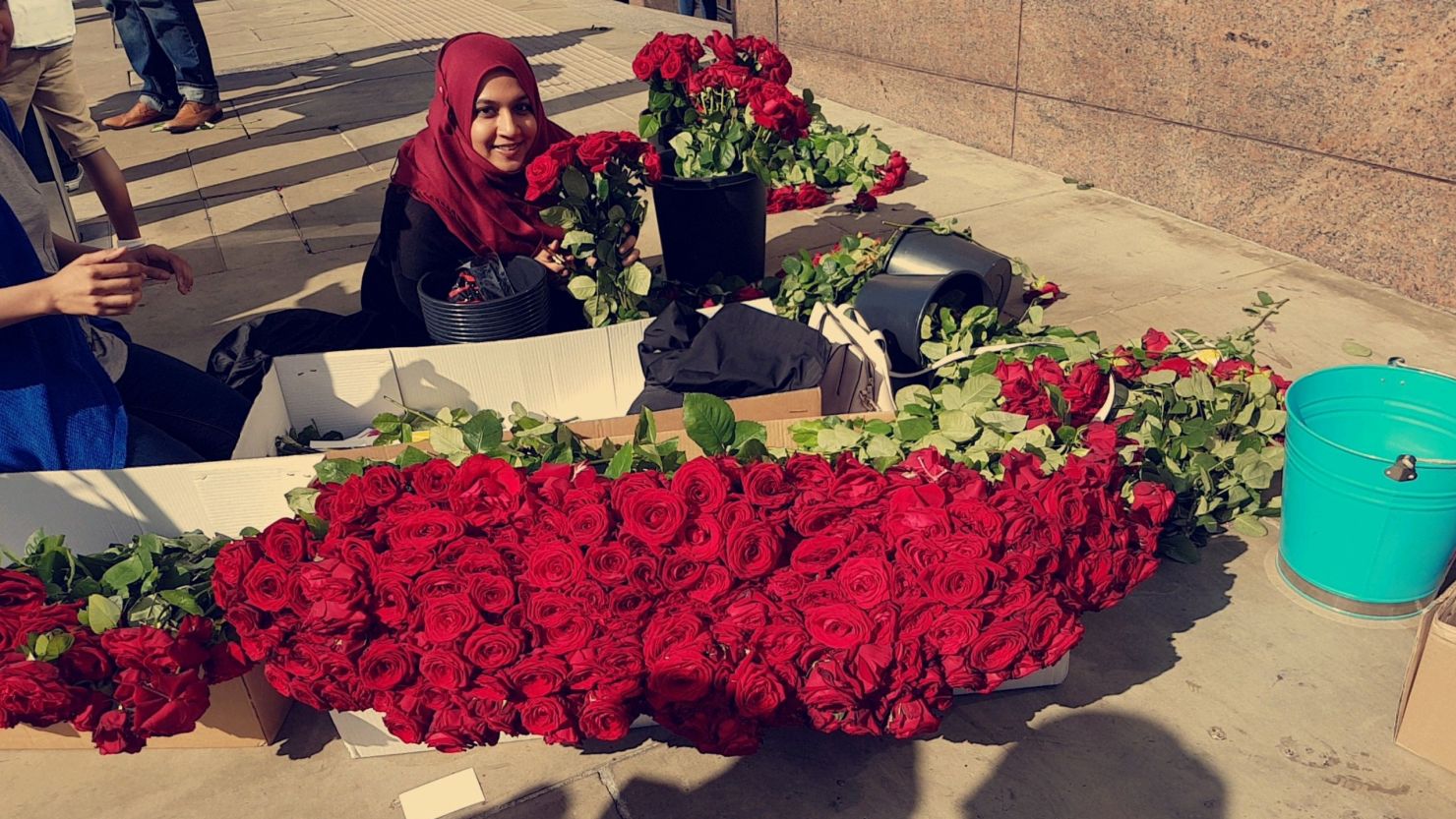 A volunteer poses by red roses given out near the London Bridge on Sunday.