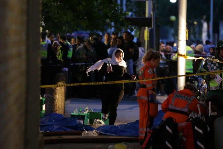 A woman runs near paramedics working near the fire.