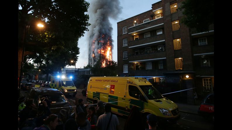 A security cordon holds people back as Grenfell Tower burns.
