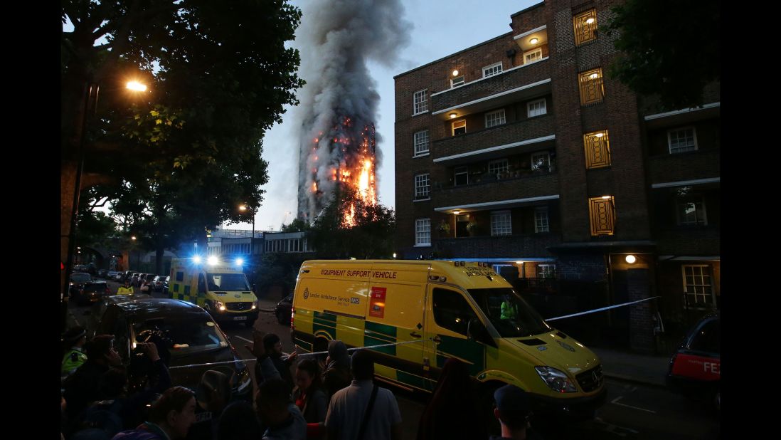 A security cordon holds people back as Grenfell Tower burns.