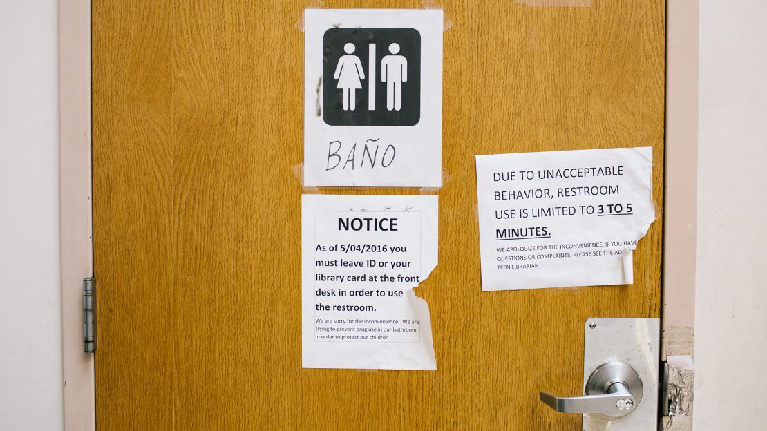 A notice on the bathroom door informs patrons of rules to use the bathroom at McPherson Square Library.