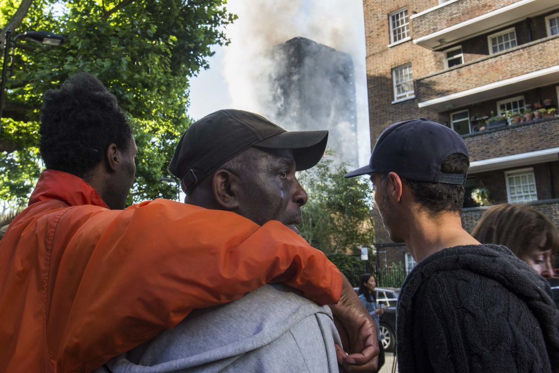 People comfort a man whose relatives lived in Grenfell Tower and hadn't yet been located since the fire.