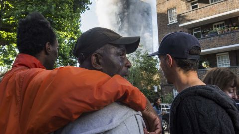 People comfort a man whose relatives lived in Grenfell Tower and hadn't yet been located since the fire.