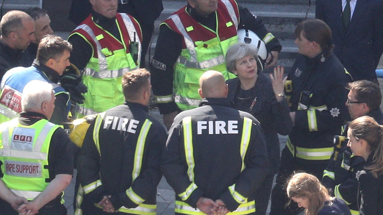 British Prime Minister Theresa May speaks to firefighters Thursday as she visits Grenfell Tower.
