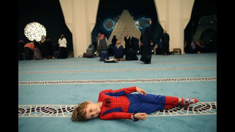 A child is dressed as Spider-Man as women pray at a mosque in Istanbul on Wednesday, June 14.