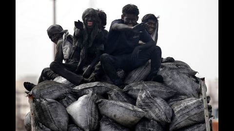 Coal workers ride on the back of a truck in Barsana, India, on Tuesday, June 13.