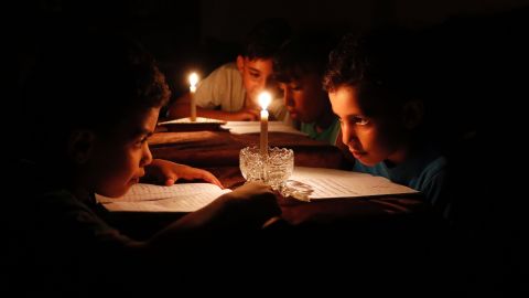 Because of electricity shortages, children in Gaza City read under candlelight on Tuesday, June 13. 