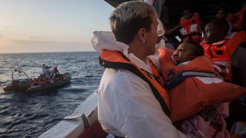 A crewmember from the Migrant Offshore Aid Station (MOAS) Phoenix vessel holds a child as they wait to transfer refugees and migrants to a waiting Italian coastguard ship after being rescued at sea off Lampedusa, Italy.