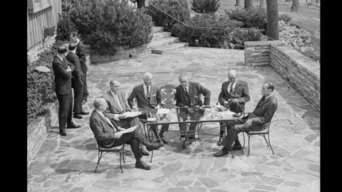 President Lyndon Johnson and members of his Cabinet hold an outdoor meeting on a Camp David patio to discuss the situation with the Vietnam War in April 1968.