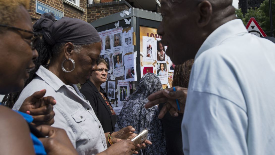 Community members exchange information near a poster board for the missing residents of Grenfell Tower.