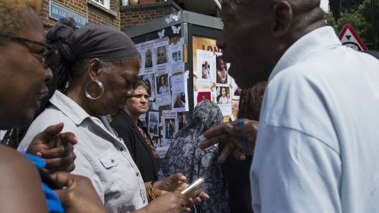 Community members exchange information near a poster board for the missing residents of Grenfell Tower.