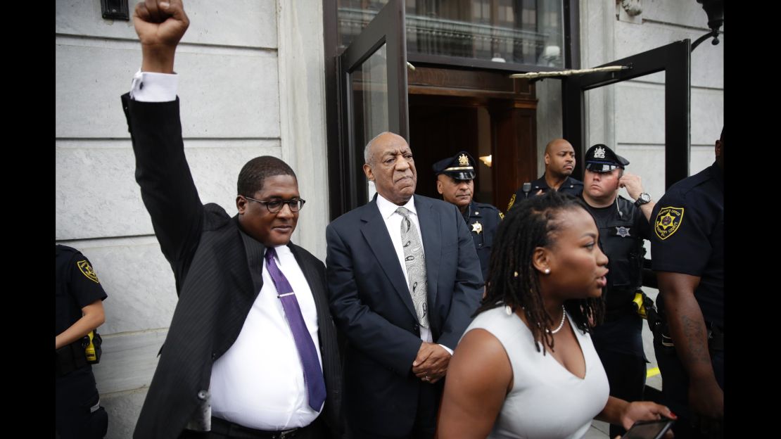 Andrew Wyatt raises his fist as Bill Cosby exits court after a mistrial was declared.