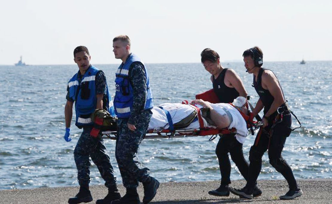 An injured USS Fitzgerald crew member is carried by US military personnel, left, and Japanese Maritime Self-Defense Force members upon arriving Saturday to the US Naval Base in Yokosuka Japan.