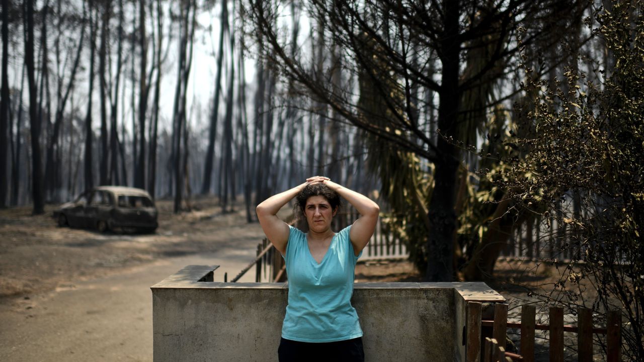 Anabela Silva stands in front of her house with her burnt car in the background after the wildfire burned through her property in Figueiro dos Vinhos.