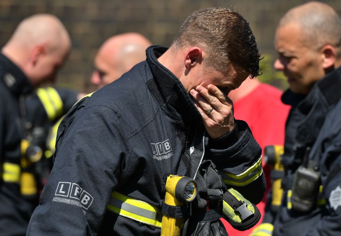 An emotional firefighter observes a moment of silence Monday near Grenfell Tower.