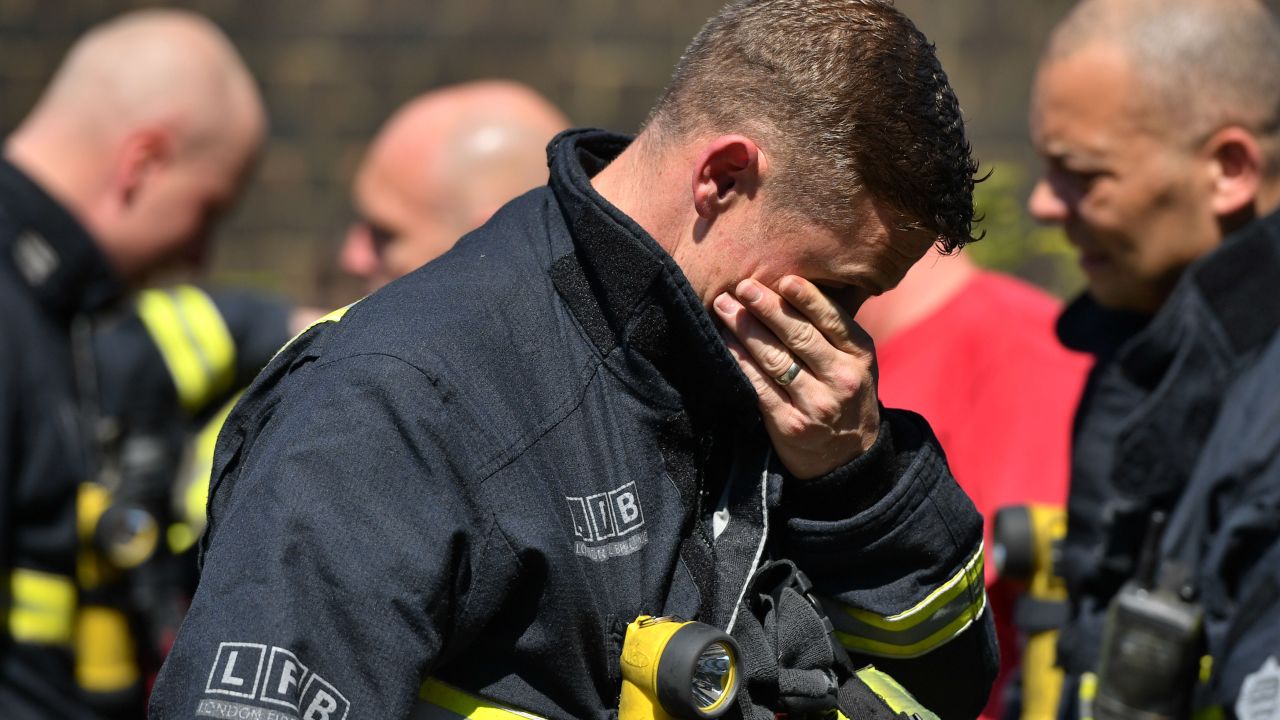 An emotional firefighter observes a moment of silence Monday near Grenfell Tower.
