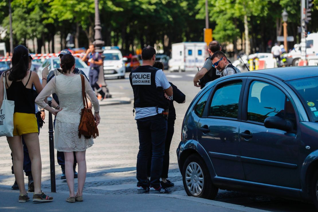 Police officers and pedestrians stand by a sealed-off area of the Champs-Elysees avenue in Paris after a car crashed into a police van Monday.